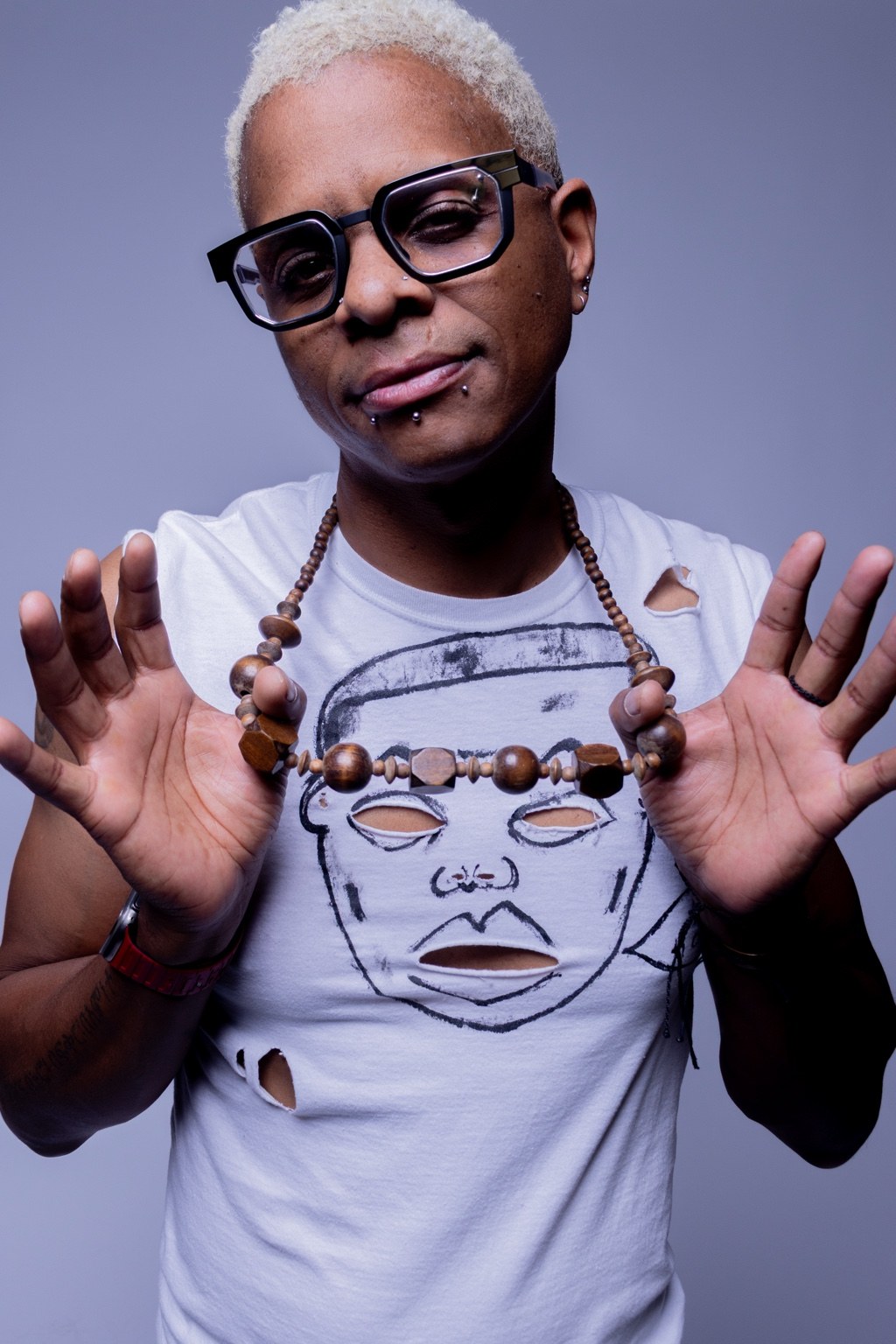 Mic Most portrait with hands raised against a studio backdrop